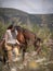 Female horse rider with yellow breeches and her brown andalusian horse grazing on a spring day in the mountains.