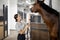 Female horseman feeding her horse in stable