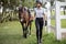 Female horseman go on lawn with Thoroughbred horse