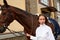 Female horseman going with her brown horse outdoor. Concept of animal care. Rural rest and leisure. Idea of green