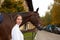 Female horseman going with her brown horse outdoor. Concept of animal care. Rural rest and leisure. Idea of green