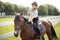 Female horseman riding brown Thoroughbred horse in summer