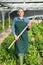 Female horticulturist with mattock working with creeping spinach in hothouse