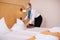 Female Housekeeper Making Bed In Hotel Room