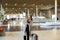 Female hurrying tourist walking in airport hall and looking at watch.