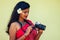 Female India photographer photographing with digital camera on the beach.beautiful indian woman in red traditional sari