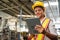 Female industrial worker working and checking machine in a large industrial factory with many equipment