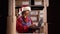 Female inventory manager wearing Santa hat checks stock, uses app on laptop computer. Hispanic woman working in a