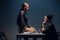 A female investigator sits on a table and interrogates a young criminal in an interrogation room