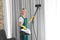 Female janitor removing dust from curtain with steam cleaner