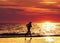 Female jogger running on beach at sunset.