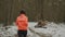 Female jogging in winter forest. Young woman running in park for lose weight. Girl intense training in isolated forest. Woman hard