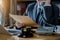 Female judge in a courtroom with the gavel, working with, computer and docking keyboard, eyeglasses, on table.