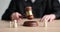 Female judge knocks gavel at table with small wooden figures