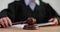 Female judge in robe hits court gavel on wooden surface