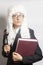 Female judge wearing a wig and Back mantle with eyeglasses holding judge gavel and book