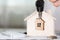 Female keeps house key on a key hanger in front of a wooden house.