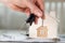 Female keeps house key on a key hanger in front of a wooden house.