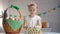 Female kid counting colored eggs and putting in basket, happy Easter greeting