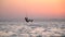 Female kite surfer is the back roll, reflection of the sunset in the sea