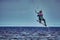 A female kiter jumps over a large lake