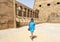 Female Korean tourist and row of ram-headed sphinxes in front of a row of columns in the first courtyard of the Temple of Amun.