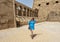 Female Korean tourist and row of ram-headed sphinxes in front of a row of columns in the first courtyard of the Temple of Amun.