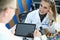 Female laborant sit on chait, examines biomaterial with microscope and communicate with pacient in clinic.