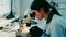 A female laboratory assistant looks into a microscope in a laboratory. Laboratory of modern medical research.