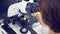 Female laboratory worker is examining a sample through an ocular of a microscope