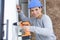 female laborer drilling hole in wall