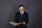 Female lawyer reads a big book with serious expression, woman in a man`s suit, tie and glasses