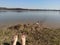 Female legs barefoot relaxing on a lake shore spring landscape