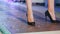 Female legs in black shiny shoes on heeled walking along podium on fashion show