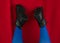 Female legs in blue tights black boots upside down on red background. Fashion modern style. Vivid contrasting colors