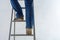 Female legs are climbing the stairs against the background of the white plastered wall. repair of premises