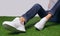 Female legs in comfort casual urban sneakers laying on the grass