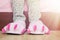 Female legs in cute pink monster foot slippers