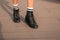 Female legs in fashionable leather black boots in stylish white striped socks. Trendy youth casual outfit. Details