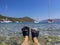 Female legs in flippers in the blue-turquoise crystal clear water on the background of Antisamos beach, Sami Kefalonia island,