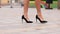 Female legs in high heels shoes walking in the urban street. Feet of young business woman in high-heeled footwear going