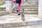Female legs and little kitten climbing up on stair steps. Young tourist calling cute abandoned hungry kitten. Authentic lifestyle