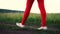 Female legs in red pants step on dirt road in the field, slow motion