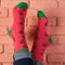 Female legs in red socks with a picture of cherry berries, leaning on a brick wall, stick up, concept, close-up