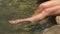 Female legs splashing river water flowing in summer forest. Young woman dipping legs in fresh water and enjoying rocky