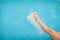 Female legs splashing water in blue swimming pool, selective focus