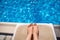 Female legs on a sun lounger on the background of the pool