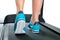 Female legs in turquoise sneakers on a treadmill