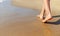 Female legs walk on the sea sand.