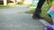 Female legs wearing black leather boots standing on asphalt road at summer. Girl in leather shoes walking on green grass